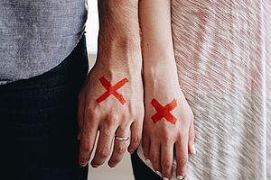 Bild Merkmale, zwei Personen halten ihre Unterarme nebeneinander, auf den Händen jeweils ein rotes Kreuz