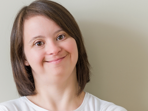 Eine junge Frau mit Down-Syndrom lacht herzlich